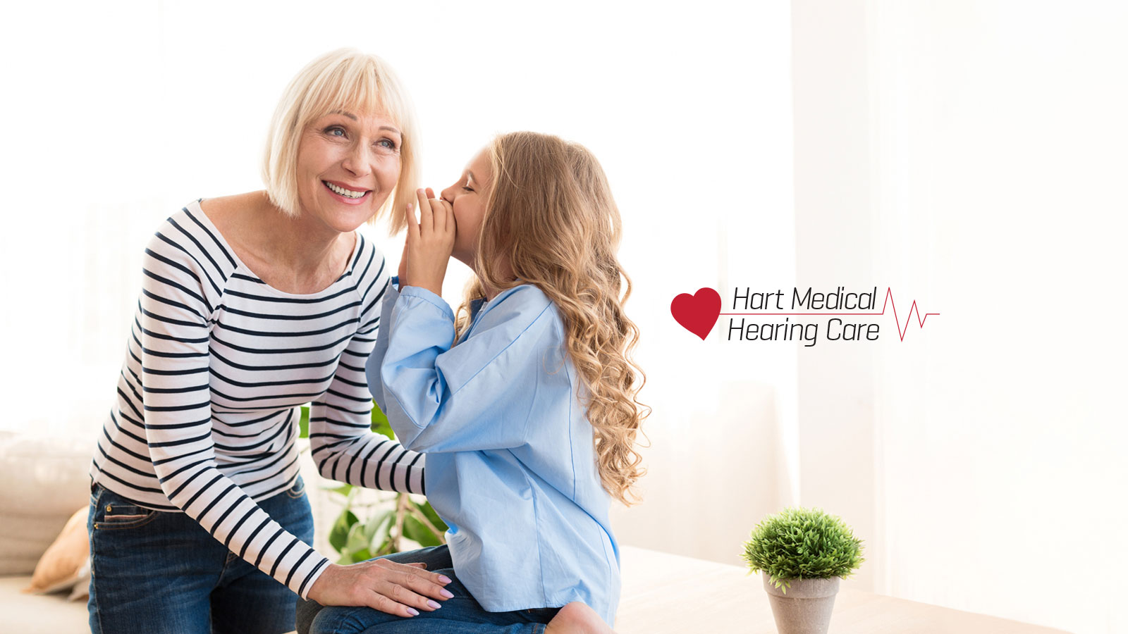 young girl speaking in older woman's ear with hart medical logo